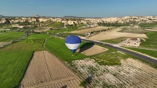 Hot air balloons fly over the mountainous landscape of Cappadocia, Turkey.