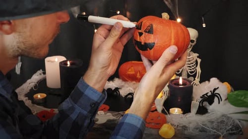 Man Decorating a Pumpkin for Halloween Indoors