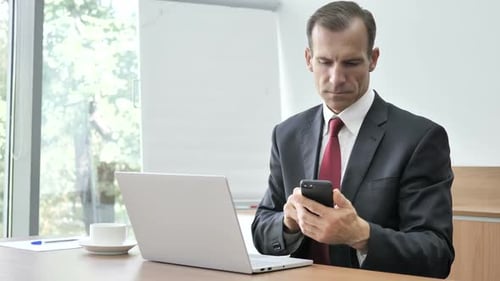Professional Man Using Phone in Office Setting