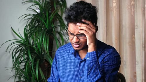 Young Adult Gripping Head and Chest in Distress