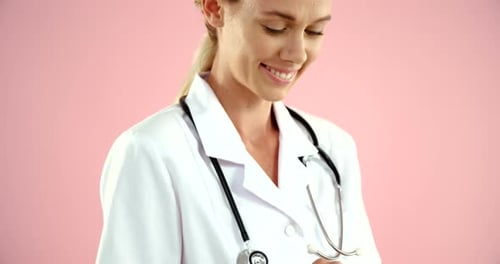 Smiling Doctor Using Tablet in Front of Pink Backdrop