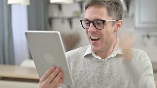 Man Celebrates Good News on Tablet Device