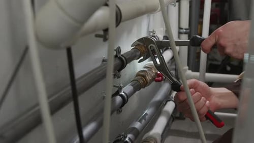Plumber Tightening Fittings on Wall Pipes with Wrench