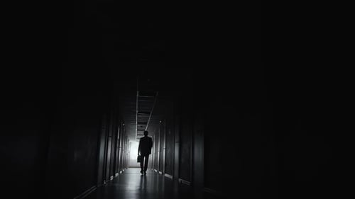 Silhouetted Man Walking Dark Hallway at Night