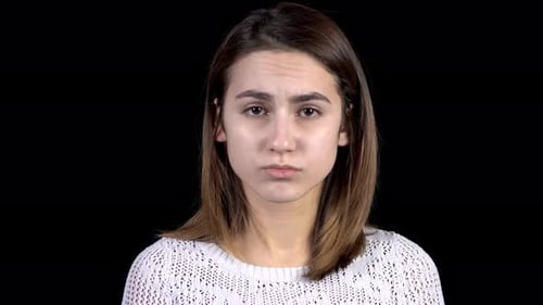 A Young Woman Shows Emotions of Sadness on Her Face. The Woman Is Sad on a Black Background Closeup