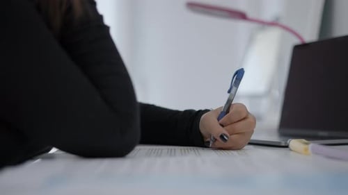 Close Up Shot of an Unrecognizable Young Girl's Hands Who is Sitting at a Desk and Writing in Her