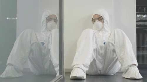 Femme épuisée portant une combinaison antivirale et un respirateur dormant au gymnase ou au bureau après la désinfection