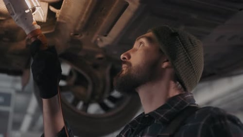 Auto Mechanic Checking Undercarriage of Car
