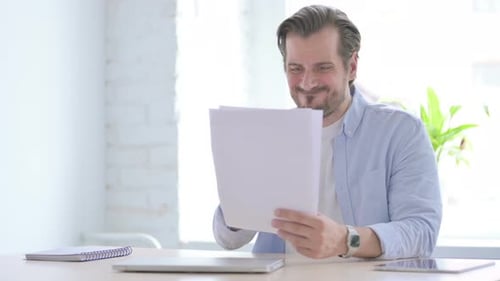 Young Man Upset While Reading Documents in Office