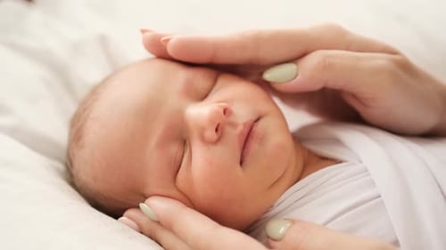 Peaceful Newborn Sleeps, Caressed by Gentle Hands