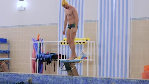 A Man Swimmer Jumping Down in the Water From the Stand