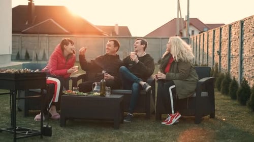 Friends Relaxing Together at Backyard Barbecue at Sunset