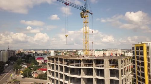Aerial view of concrete frame of tall apartment building under construction in a city.