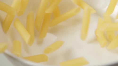 Dry Penne Pasta Poured Into White Bowl