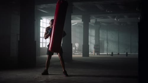 Muscular Man Training With Punching Bag In Gym