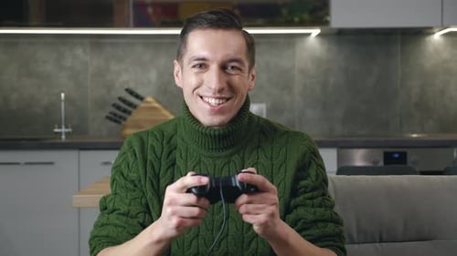 Enthusiastic man in green sweater playing video games