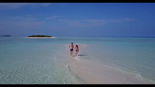 Young couple happy together on relaxing coastline beach trip by aqua blue lagoon and white sandy bac