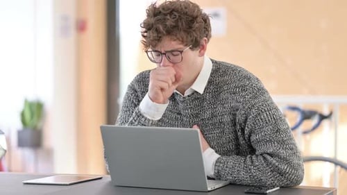 Young Adult Coughing at Desk while Working