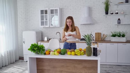 Woman Eating Healthy Fruit Salad in Bright Kitchen