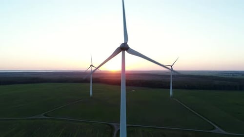 Wind Turbines Spinning in Field at Sunset