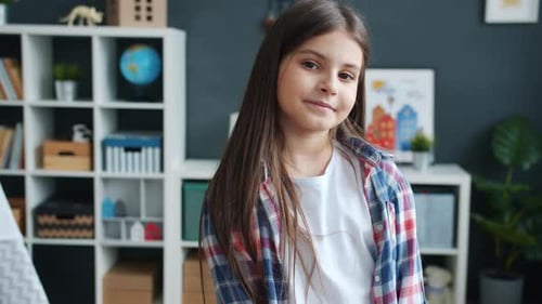 Замедленное движение портрет очаровательной девушки, улыбающейся и смотрящей в камеру в уютной детской комнате