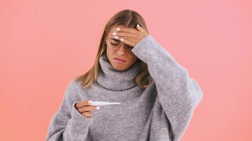 Woman Holds Thermometer, Feeling Unwell