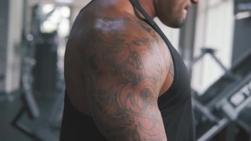Tattooed Man Working Out at Gym