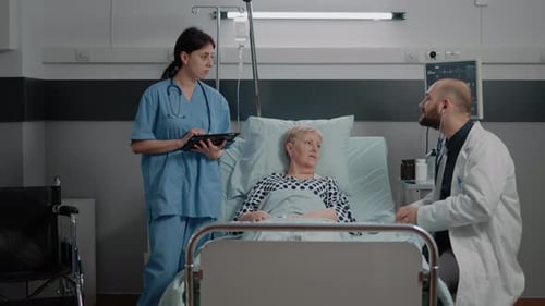 Doctor Examines Senior Patient in Hospital with Nurse