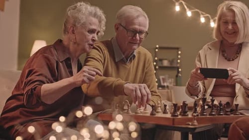 Happy Senior Couple Winning Chess Game Playing with Friends