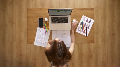 Woman Working on Laptop with Art Drawings