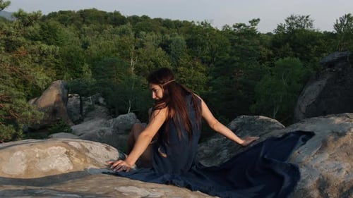 In a Blue Silk Dress a Young Woman Sat on Rocky Terrain Relaxing Outdoors in a Travel Lifestyle