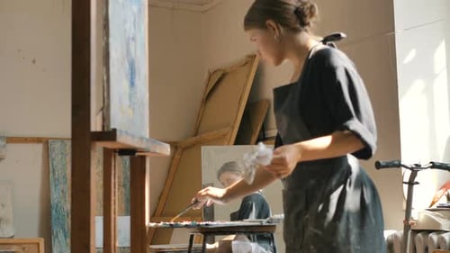 Female Artist Painting on Canvas in Sunny Studio