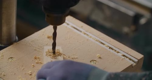 Carpenter Drills Holes in Wooden Plank with Drilling Machine in Slow Motion Carpentry at Workshop
