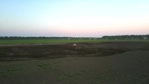 Tractor Plows Field with Harrow at Green Meadow Aerial View