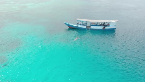 Aerial: woman swimming on turquoise water coral reef tropical caribbean sea