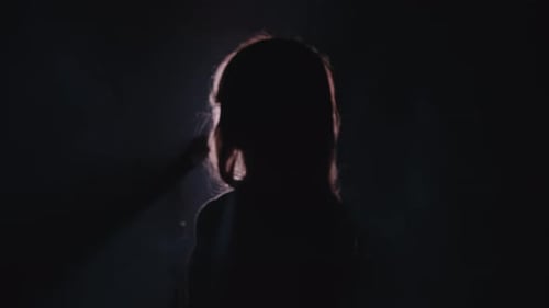 Close-up of the Face of the Singer with Microphone on a Black Smoky Background. The Singer Sings a