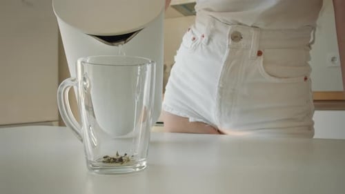 Woman Pours Hot Water into Tea Mug
