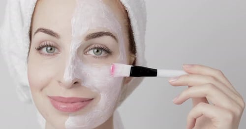 Woman Applies White Facial Mask With Brush