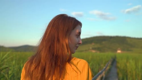 Woman Walking on Bridge in Rural Meadow at Sunset