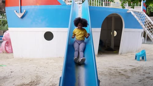 4K Little African girl sliding and playing at playground in the park