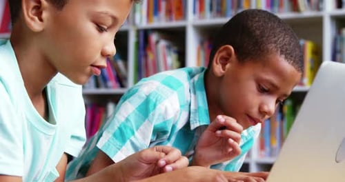 Schoolkids using laptop in library at school