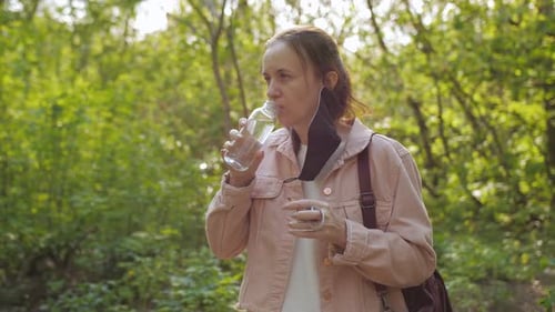 The Woman Removes the Protective Medical Mask From Her Face To Drink Water