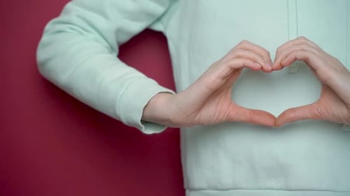 Close-up of female hands showing heart on red background