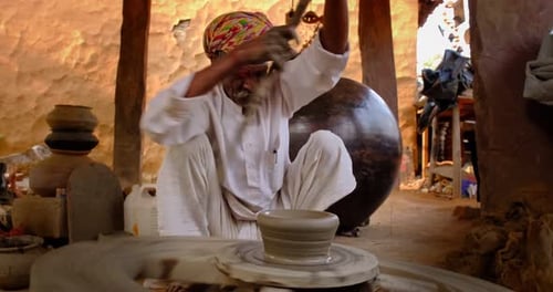 Potier professionnel qualifié lançant le volant du potier et façonnant un récipient en céramique traditionnel et
