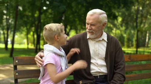 Grandson Sharing Secrets With Grandfather, Sitting in Park, Trusting Relations