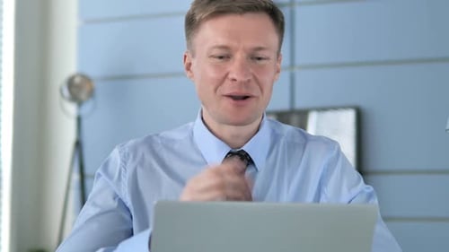 Enthusiastic Man Communicating on Laptop in Office