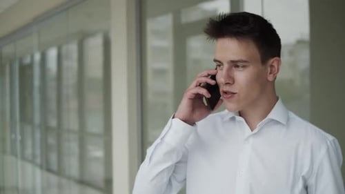 Young Adult Man Talking on Cellphone Inside Building