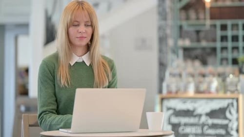 Young Woman Coughing While Using Laptop in Cafe