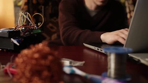 Adult Working On Laptop With Electronics