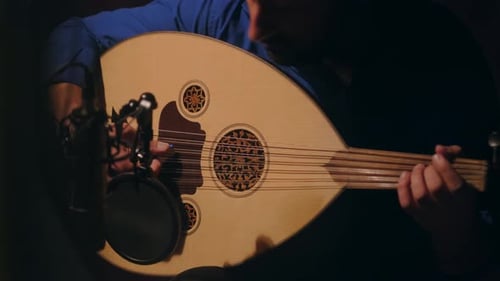 Man Plays Stringed Instrument in Dark Room